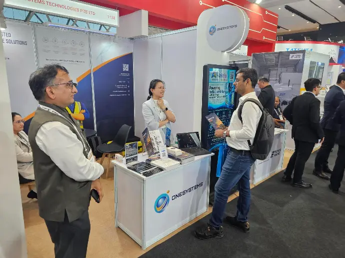 OneSystems representatives speaking with a visitor at SEMICON India 2026
